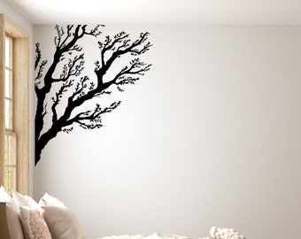 Könnte beinhalten: Ein Schlafzimmer mit einem Bett, das mit einer weißen Decke und einer braunen Strickdecke bedeckt ist. Das Bett steht an einer weißen Wand mit einer schwarzen Silhouette eines Baumzweigs. Neben dem Bett steht ein Korb aus Weide auf dem Boden.