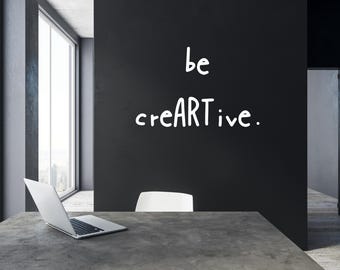 May include: A modern office space with a large window, a laptop on a desk, and a white chair. The wall has the words "be creative" written on it in white.