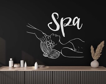 May include: A black and white illustration of a person receiving a spa treatment, with the word "Spa" written above. The illustration is on a black wall, with a wooden shelf below it. There are three bottles and a jar on the shelf.