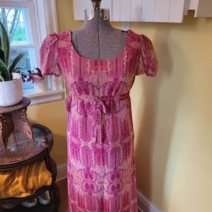 1970's does regency psychedelic pink dress with sheer puff sleeves and bow detail at waist. Bust 35" - Underbust 29" - Waist 31" - Hips 35"