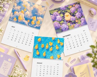 Könnte beinhalten: Drei Wandkalender für 2027 mit gelben Enten-Illustrationen für Juli, August und September. Juli zeigt Enten in Wolken, August Enten in einem Pool und September eine Ente in lila Blumen. Schreibwaren wie ein Stift, Büroklammern und Notizbücher sind ebenfalls abgebildet.