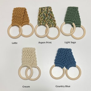 May include: Five crochet towel holders in various colors: Latte, Aspen Print, Light Sage, Cream, and Country Blue. Each holder features a wooden ring design and is labeled with its respective color name.