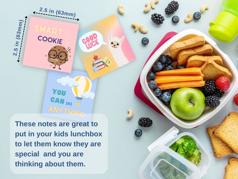 May include: Three colorful 2.5 inch square motivational notes with cute illustrations and encouraging messages: "Smart Cookie", "Good Luck", and "You Can Do Anything". The notes are next to a lunchbox filled with healthy snacks like fruit, vegetables, and crackers.