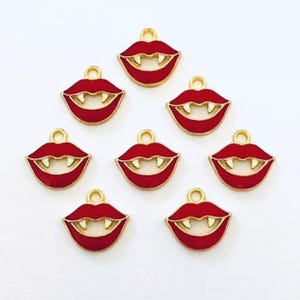 May include: Eight red enamel vampire mouth charms with gold-colored trim and fangs. Each charm has a small loop at the top for attaching to jewelry or other crafts. The charms are arranged on a white background.