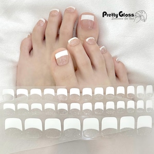 May include: White and clear glitter toe nail stickers with a white tip. The stickers are arranged in rows on a clear sheet. The image also shows a pair of feet with the stickers applied to the toenails.