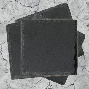a set of three slate coasters sitting on top of a marble counter