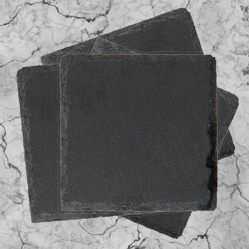 a set of three slate coasters sitting on top of a marble counter