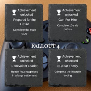 Puede incluir: Cuatro posavasos cuadrados de pizarra gris oscuro con texto blanco y gr&aacute;ficos de trofeos. Cada posavasos muestra un logro diferente del videojuego Fallout 4. El t&iacute;tulo del juego est&aacute; centrado.