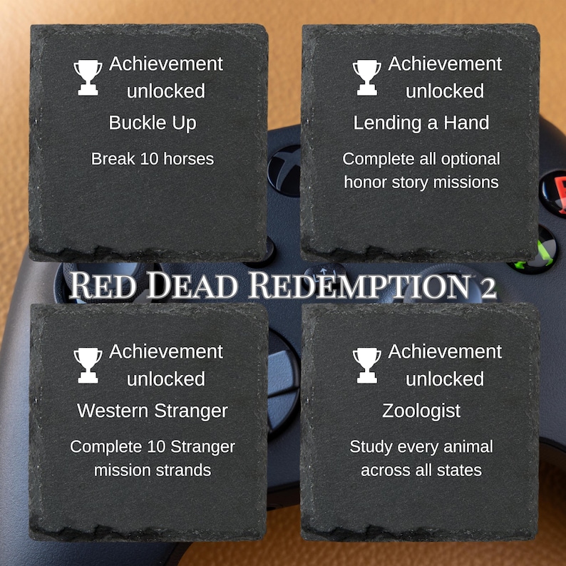 Puede incluir: Cuatro posavasos cuadrados de pizarra con texto blanco y gr&aacute;ficos de trofeos. Cada posavasos muestra un logro del videojuego Red Dead Redemption 2. Los logros incluyen "Buckle Up", "Lending a Hand", "Western Stranger" y "Zoologist".