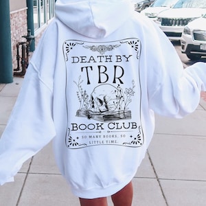 K&ouml;nnte beinhalten: Wei&szlig;er Kapuzenpullover mit einem schwarz-wei&szlig;en Grafikdruck auf der R&uuml;ckseite. Die Grafik zeigt einen Sch&auml;del, Blumen und den Text "Death by TBR Book Club. So many books, so little time."