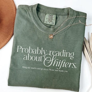 May include: A green t-shirt with the text "Probably reading about Shifters. Bring me snacks and go away. Please and thank you." printed in white.