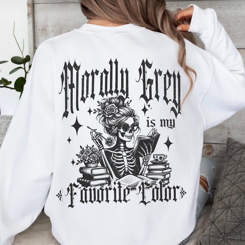 May include: White sweatshirt with a black graphic of a skeleton reading a book, smoking, and wearing sunglasses. The text "Morally Grey is my Favorite Color" is printed above and below the graphic in a gothic font.