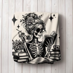 May include: Black and white illustration of a skeleton woman with flowers in her hair reading a book. She is sitting at a table with a cup of tea and a stack of books.