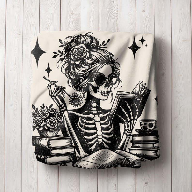 May include: Black and white illustration of a skeleton woman with flowers in her hair reading a book. She is sitting at a table with a cup of tea and a stack of books.