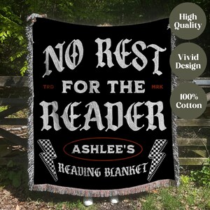May include: Black reading blanket with white text that reads "NO REST FOR THE READER". The blanket includes the name "ASHLEE'S" and the words "READING BLANKET". The blanket has a checkered flag and lightning bolt design.
