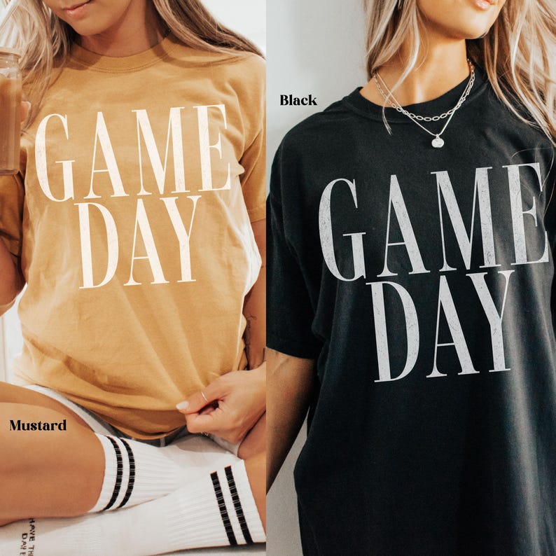 May include: Two short-sleeve t-shirts, one in mustard yellow and one in black, both featuring the text GAME DAY printed in large white capital letters across the chest. The mustard shirt is labelled Mustard and the black shirt is labelled Black.