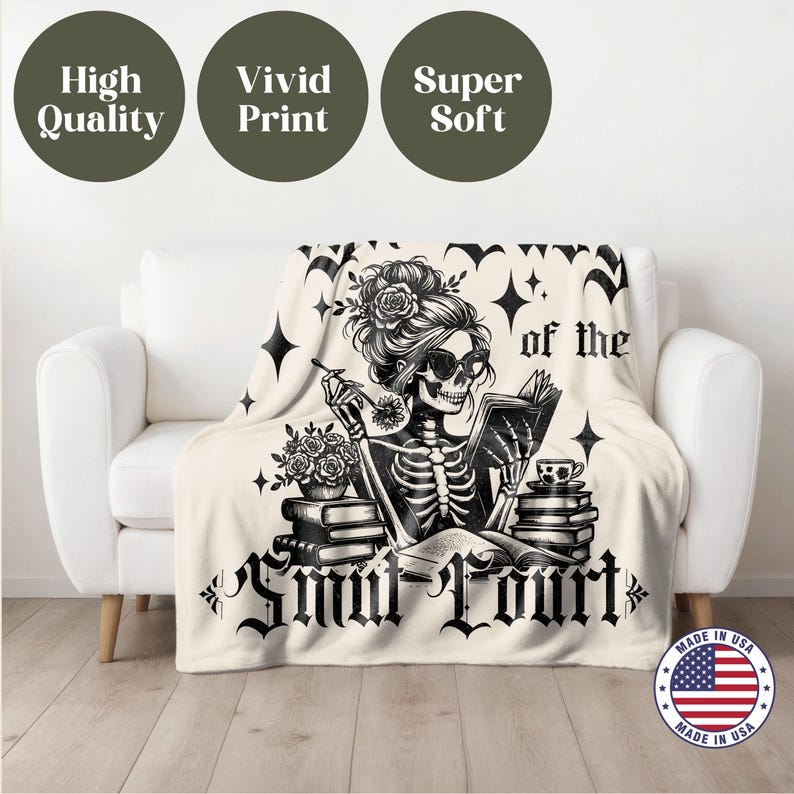 May include: A white throw blanket with a black and white illustration of a skeleton reading a book. The text "of the Smut Court" is printed on the blanket. The blanket is made in the USA.