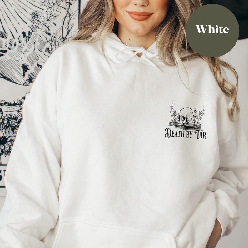 K&ouml;nnte beinhalten: Wei&szlig;er Kapuzenpullover mit einem schwarzen Grafikdruck eines Sch&auml;dels auf einem Buch mit dem Text "Death by TBR".