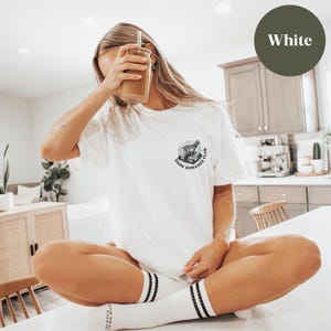 May include: White t-shirt with a black and white graphic of a book with an eye and the text "Dark Romance Club".