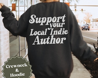 May include: Dark gray crewneck sweatshirt with the text "Support your Local Indie Author" in white script across the back. A small graphic at the bottom left corner reads "Crewneck & Hoodie Option".
