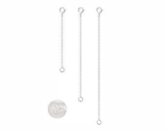 Può includere: Tre catenelle di estensione in metallo color argento di lunghezze variabili, ciascuna dotata di una chiusura a molla circolare a un'estremità e un piccolo anellino all'altra. Un'etichetta metallica circolare con la scritta S925 è posta sotto.