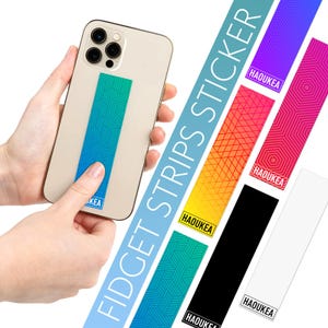 May include: A smartphone with a blue and green geometric pattern fidget strip attached. Several colorful fidget strips with geometric designs are displayed, including purple, red, yellow, black, and white. The text "FIDGET STRIPS STICKER" is visible.
