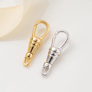 May include: Two metal swivel lobster claw clasps, one finished in a polished gold tone and the other in a polished silver tone. Each clasp features a spring-loaded gate mechanism and a rotating base, designed for secure attachment to various items.