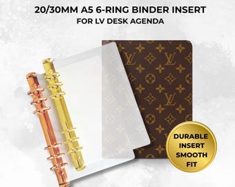 May include: A 20/30mm A5 6-ring binder insert for LV desk agenda featuring two metallic ring mechanisms in gold and rose gold tones, a clear plastic sheet, and a brown cover with a repeating monogram pattern. Text reads: DURABLE INSERT SMOOTH FIT.