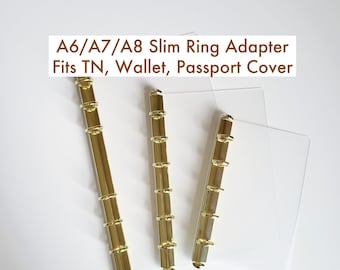 May include: Three gold-colored slim ring adapters for A6, A7, and A8 sizes, suitable for TN, wallet, and passport covers. The adapters are displayed against a white background, with the text "A6/A7/A8 Slim Ring Adapter Fits TN, Wallet, Passport Cover".