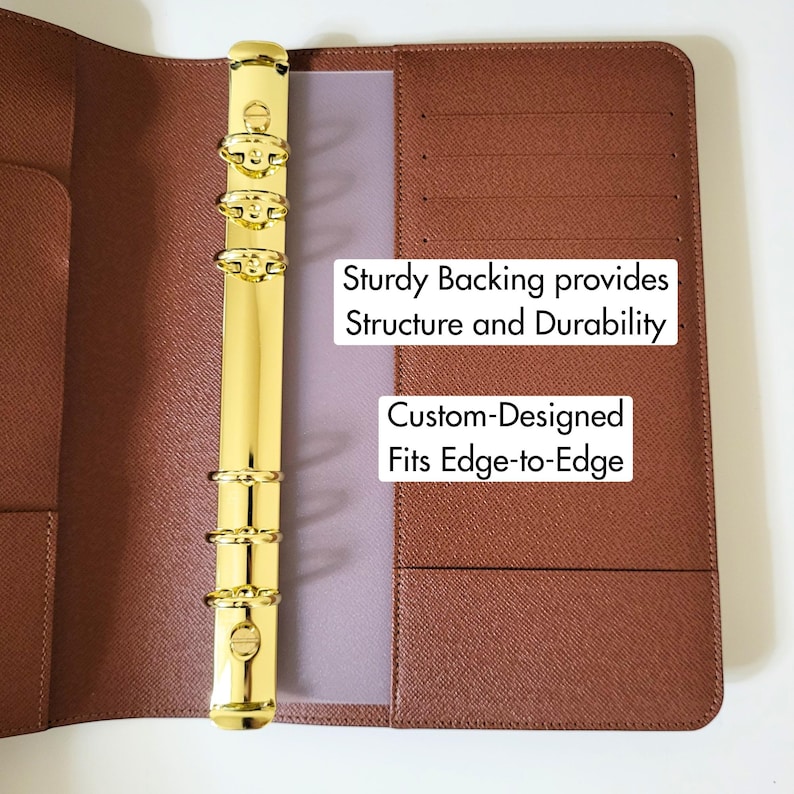 May include: A brown textured planner binder featuring a gold-colored six-ring metal mechanism. The interior includes card slots and pockets. Text on the binder reads: Sturdy Backing provides Structure and Durability, Custom-Designed Fits Edge-to-Edge.