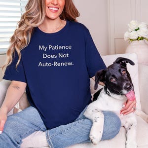 May include: A navy blue short-sleeved t-shirt featuring the white text "My Patience Does Not Auto-Renew." The shirt is paired with light blue denim jeans, creating a casual look that highlights the bold, centered lettering on the chest.