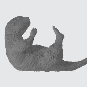 May include: A grey otter figurine lying on its back with its paws in the air.