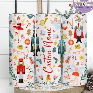 May include: Three stainless steel tumblers with a festive Nutcracker theme. Each tumbler features a repeating pattern of ballet dancers, toy soldiers, and holiday ornaments. The center tumbler has the text "Custom Name" in red script.