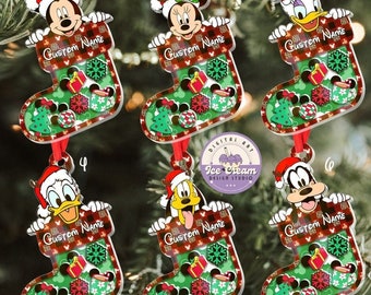 May include: Six Christmas ornaments featuring different Disney characters. Each ornament is a stocking with a red and black plaid pattern and a green background. The characters are Mickey Mouse, Minnie Mouse, Donald Duck, Daisy Duck, Goofy, and Pluto. Each ornament has the text "Custom Name" on it.
