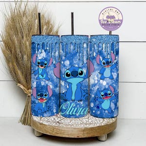 May include: Three blue and white glitter tumblers with a blue Stitch character from Lilo & Stitch. The middle tumbler has the name "Olivia" written on it.