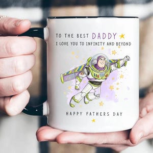 Puede incluir: Taza de cer&aacute;mica blanca con asa y borde negros. La taza presenta un gr&aacute;fico de Buzz Lightyear y el texto "TO THE BEST DADDY, I LOVE YOU TO INFINITY AND BEYOND, HAPPY FATHERS DAY."