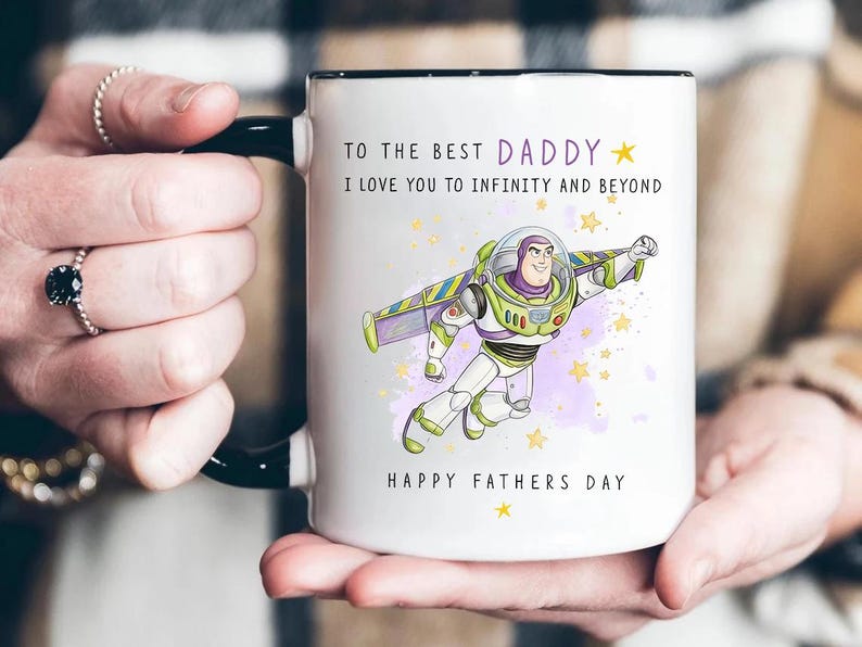 Puede incluir: Taza de cer&aacute;mica blanca con asa y borde negros. La taza presenta un gr&aacute;fico de Buzz Lightyear y el texto "TO THE BEST DADDY, I LOVE YOU TO INFINITY AND BEYOND, HAPPY FATHERS DAY."
