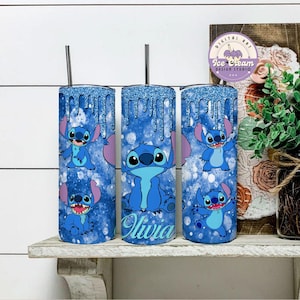May include: Three stainless steel tumblers with a blue glitter background and a cartoon Stitch character design. The middle tumbler has the name "Olivia" written on it.