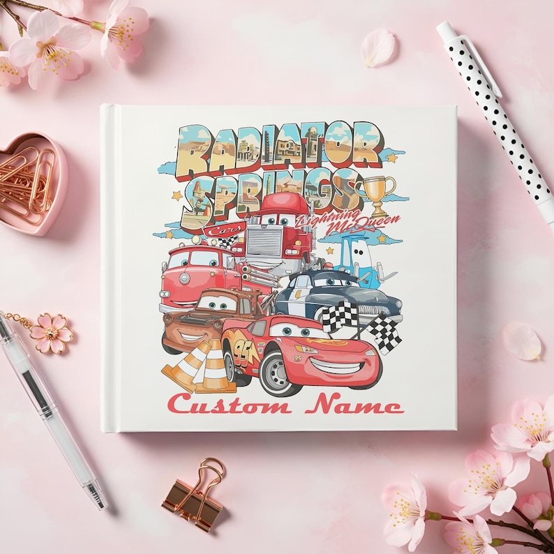 Puede incluir: Una portada de libro blanca con una colorida ilustraci&oacute;n de personajes de la pel&iacute;cula Cars, incluyendo a Rayo McQueen y otros veh&iacute;culos. El texto "Radiator Springs" y "Custom Name" tambi&eacute;n son visibles.