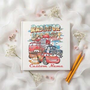 Puede incluir: Un libro blanco con una colorida ilustraci&oacute;n de personajes de la pel&iacute;cula Cars, incluyendo a Rayo McQueen y Mate. La portada del libro presenta el texto "Radiator Springs" y "Custom Name".