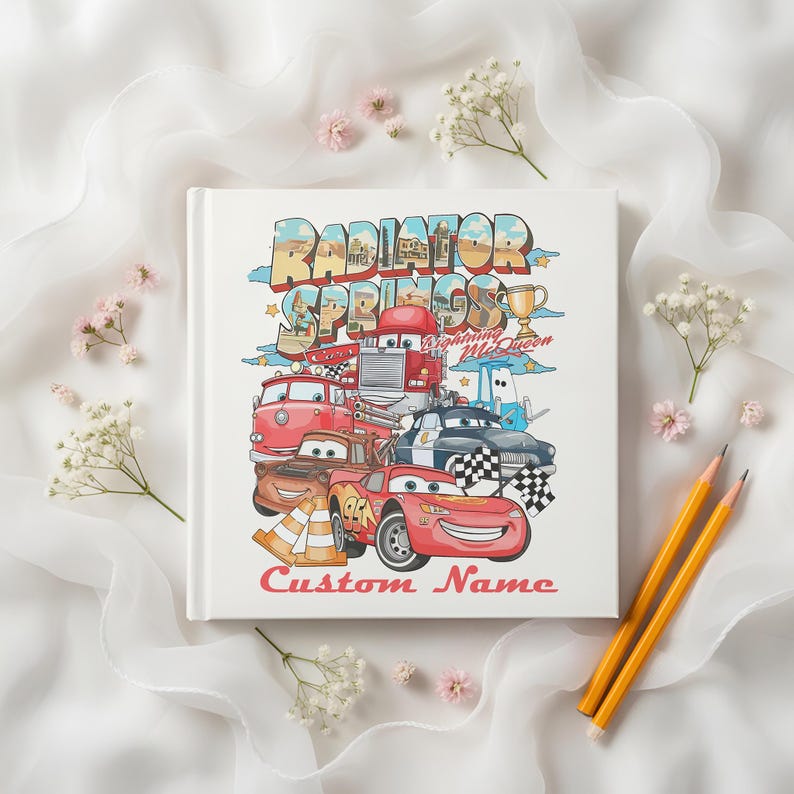 Puede incluir: Un libro blanco con una colorida ilustraci&oacute;n de personajes de la pel&iacute;cula Cars, incluyendo a Rayo McQueen y Mate. La portada del libro presenta el texto "Radiator Springs" y "Custom Name".