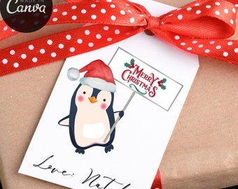 May include: A white gift tag with a cartoon penguin wearing a Santa hat, holding a sign that says "Merry Christmas." The tag is tied with a red ribbon with white polka dots. The text "Love, Natalie" is written at the bottom.