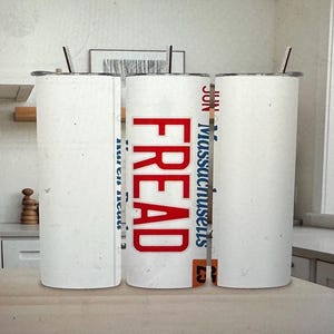 May include: Three white insulated tumblers with silver lids and straws. The center tumbler has the word "FREAD" in red block letters. The right tumbler has the word "Massachusetts" in blue letters.