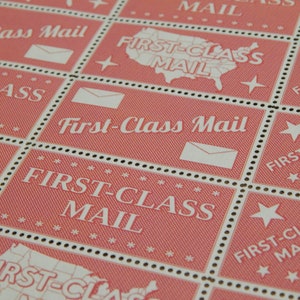 May include: A close-up of several red and white postage stamps with the text "First-Class Mail" repeated on each stamp. The stamps feature a stylized image of the United States.