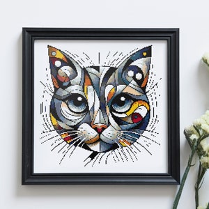 May include: A framed abstract painting of a cat's face in a geometric style. The cat's face is made up of various shapes and colors, including blue, yellow, red, and white.