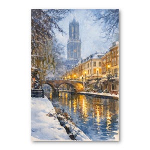 May include: Watercolor painting of a snow-covered European city scene. A bridge arches over a canal reflecting the warm glow of streetlights. A tall church tower rises in the background, with buildings lining the canal.