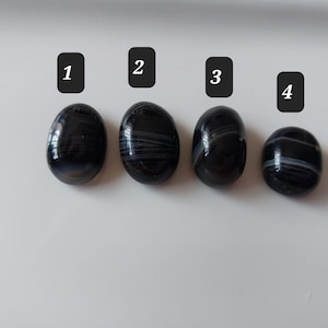 Puede incluir: Cuatro piedras de ágata negras y blancas con rayas blancas. Las piedras están numeradas del 1 al 4.