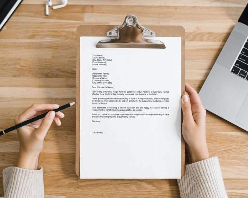 May include: A white sheet of paper with a typed resignation letter on a clipboard. The letter is being reviewed by a person holding a black pencil.