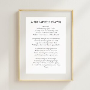 May include: A framed print featuring the text "A Therapist's Prayer" in a black, elegant font. The print is set against a white background and enclosed in a light-colored wooden frame, suitable for a counseling office or home decor.