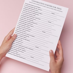 K&ouml;nnte beinhalten: Ein wei&szlig;es Blatt Papier mit dem Text "CONVERSATION STARTERS FOR TEENS" in Schwarz. Das Papier wird von H&auml;nden vor einem rosa Hintergrund gehalten. Der Text enth&auml;lt Aufforderungen zum Teilen von Gedanken, Gef&uuml;hlen und Erfahrungen.